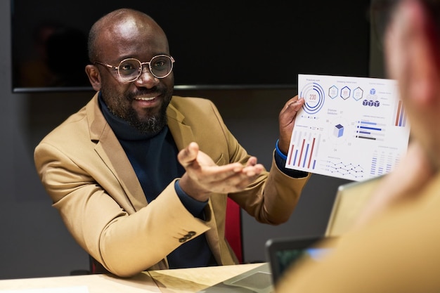 Jeune analyste confiant avec un document papier financier parlant à un collègue