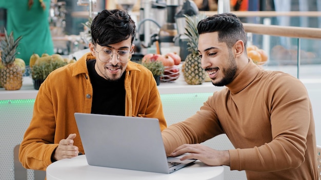 Un jeune arabe motivé montre à un ami de nouvelles réalisations d'applications sur un ordinateur portable indien