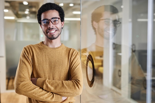 Un jeune Arabe portant des lunettes au bureau et souriant à la caméra.