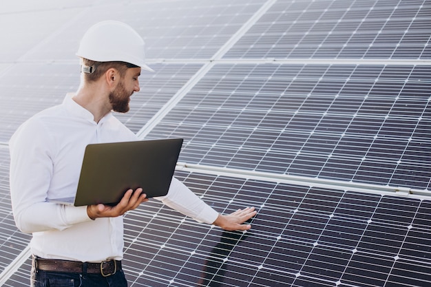 Jeune architecte debout près de panneaux solaires faisant des diagnostics sur ordinateur