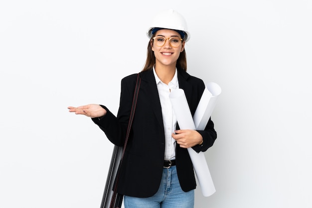 Jeune architecte femme de race blanche avec casque et tenant des plans sur fond isolé holding copyspace imaginaire sur la paume