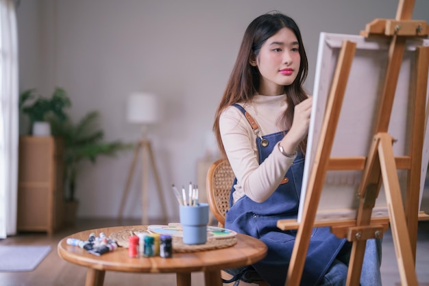 Jeune artiste asiatique travaillant au dessin et à la peinture pour créer des œuvres d'art créatives sur la toile