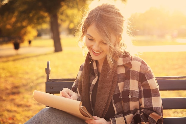 Jeune artiste féminine dessinant un croquis assis sur un banc dans un magnifique parc