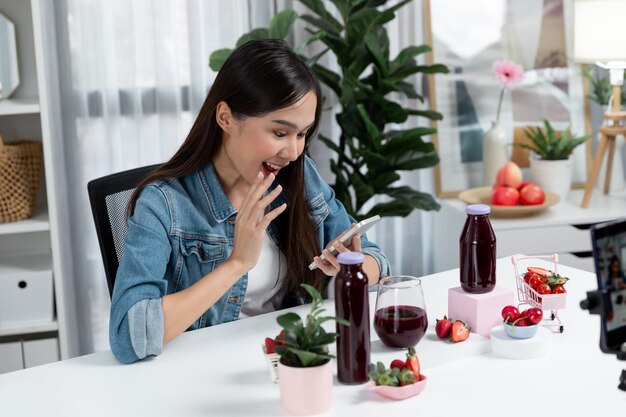 Jeune asiatique faisant la critique de délicieuses boissons mélangées de jus de fraise et de cerise stratagème