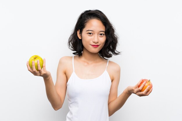 Jeune asiatique avec une pomme sur un mur blanc isolé