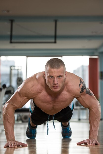 Photo jeune athlète adulte faisant des pompes dans le cadre d'une formation de musculation