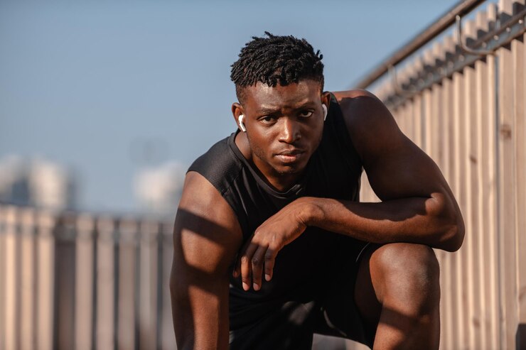 Photo jeune athlète africain en vêtements de sport regardant la caméra alors qu'il se tient à l'extérieur