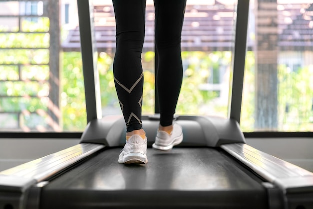 Jeune athlète asiatique heureuse courir sur un tapis roulant en cours d'exécution dans une salle de sport intérieure fitness pour la santé