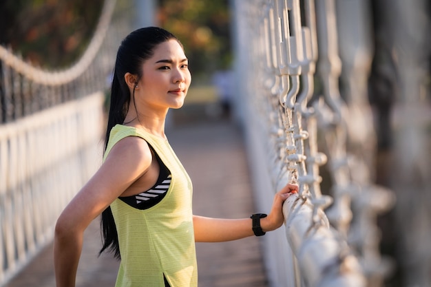 Une jeune athlète asiatique en tenue de sport faisant des étirements et s'échauffant avant une séance d'entraînement, de jogging et de remise en forme dans le parc de la ville le matin. Sports et loisirs