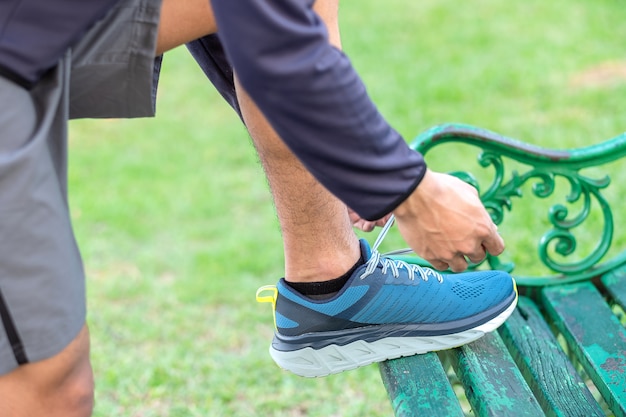 Jeune athlète attachant des chaussures de course dans le parc en plein air