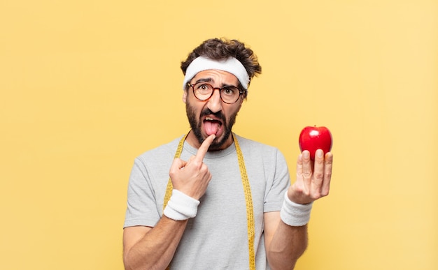 Jeune athlète barbu fou expression en colère et tenant une pomme et tenant une pomme