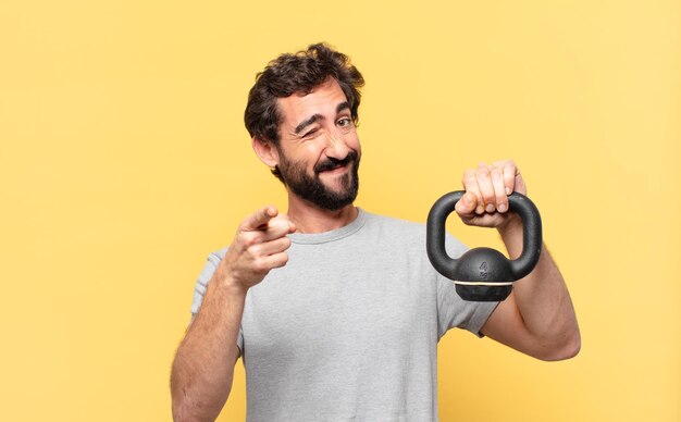 Jeune athlète barbu fou pointant ou montrant et tenant un haltère