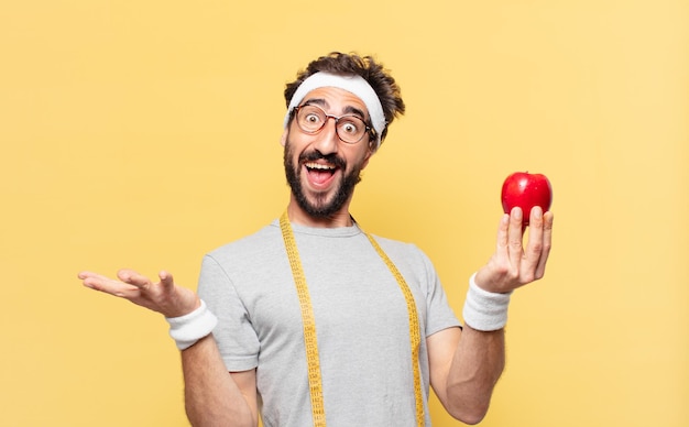 Jeune athlète barbu fou surpris expression et tenant une pomme et tenant une pomme