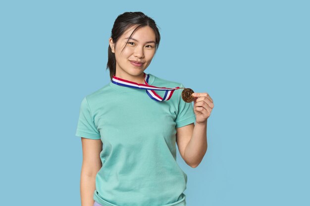 Jeune athlète chinois joyeux avec une médaille en studio