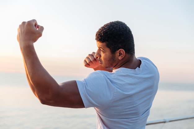 Jeune athlète debout et pratiquant la boxe de l'ombre à l'extérieur