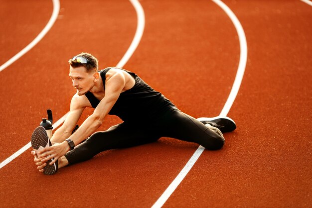 Jeune athlète faisant des étirements avant de courir au stade Photo de haute qualité