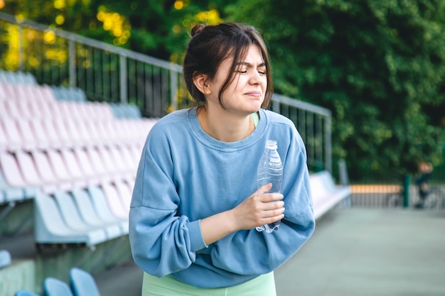 Une jeune athlète féminine boit de l'eau après s'être entraînée