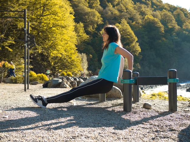 Une jeune athlète féminine fait des pompes depuis le banc. Activités sportives de plein air.