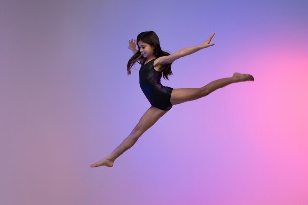 jeune athlète gymnaste effectuant des sauts s'entraînant pour un fond coloré de compétition dans un studio