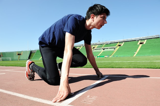 jeune athlète masculin est au départ du tapis roulant au stade