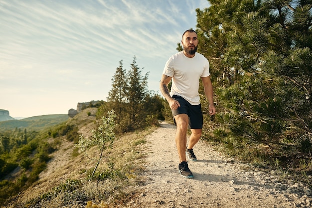 Jeune athlète masculin musclé courant jusqu'à la colline