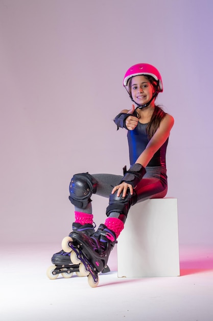 jeune athlète patineur avec casque rose et équipement de protection pour photo de studio de compétition