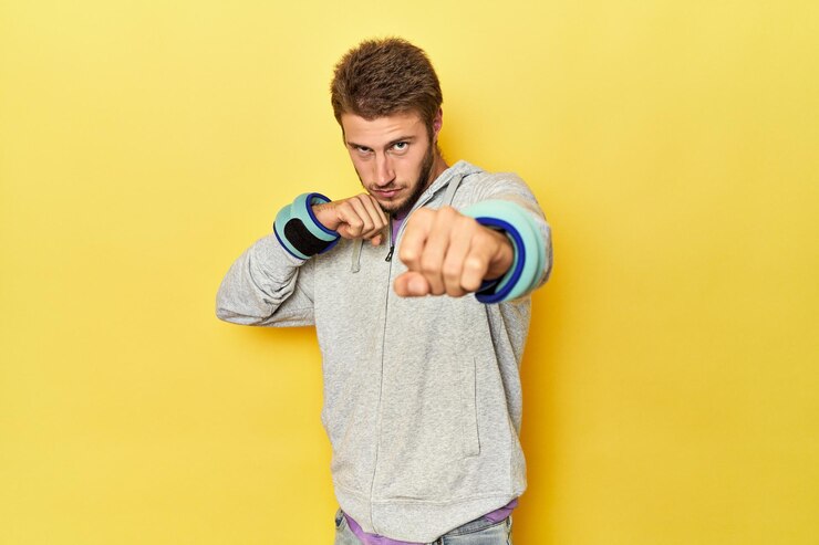 Photo jeune athlète avec des poids au poignet en boxe sur un fond de studio jaune