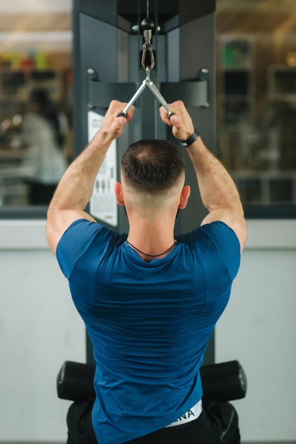 Un jeune athlète s'entraîne dans la salle de sport Montre les muscles du dos et de la poitrine Vue arrière