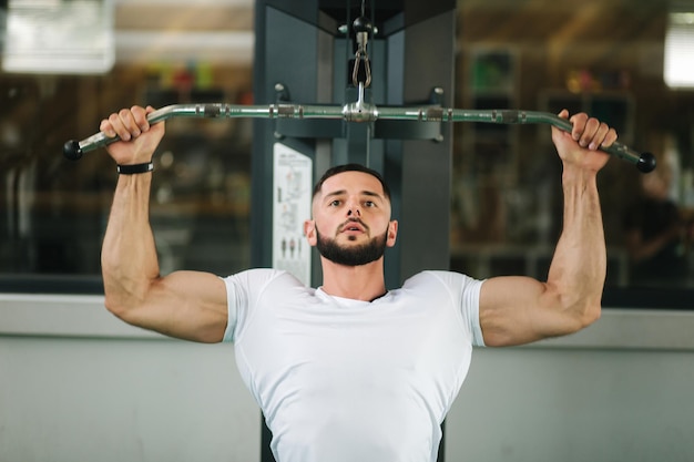 Un jeune athlète s'entraîne dans la salle de sport Montre les muscles du dos et de la poitrine