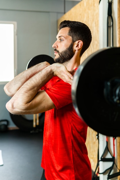 Jeune athlète soulevant des haltères avec des haltères s'exerçant dans une salle de sport