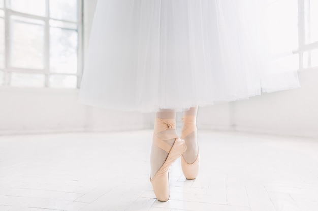 Jeune ballerine dansant, gros plan sur les jambes et les chaussures, debout en position de pointe.