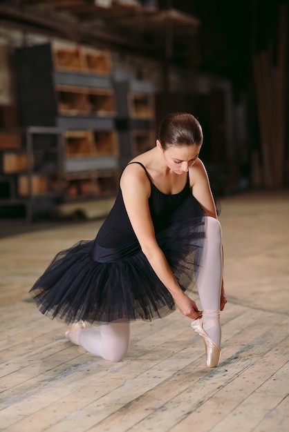 La jeune ballerine en robe noire s'entraîne dans les coulisses.