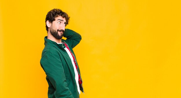 Jeune barbu fou contre le mur orange