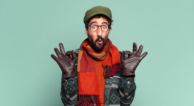 Photo jeune barbu fou. expression heureuse et surprise et portant des vêtements d'hiver