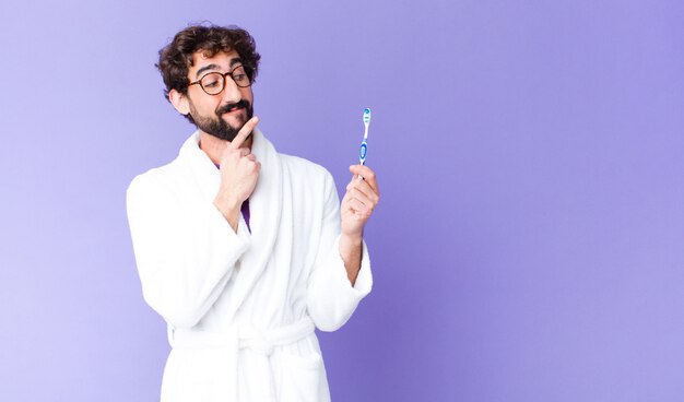 Jeune barbu fou portant un peignoir et une brosse à dents.