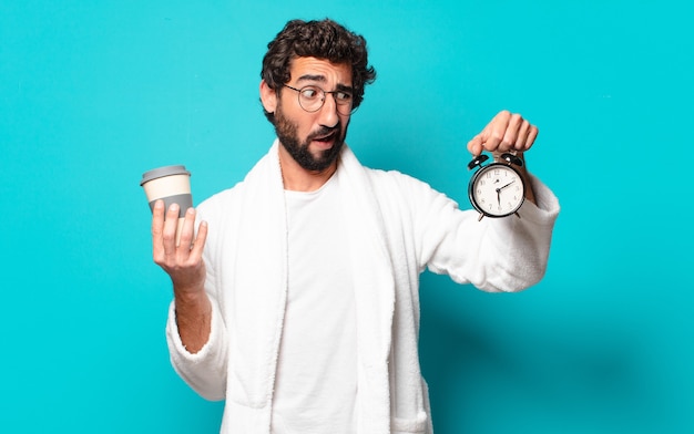 Jeune barbu fou portant un peignoir et un réveil