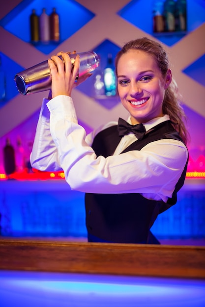 Jeune barmaid avec cocktail shaker au comptoir