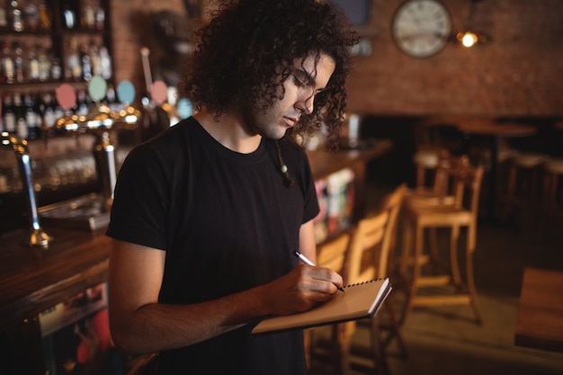 Jeune barman écrit sur le journal