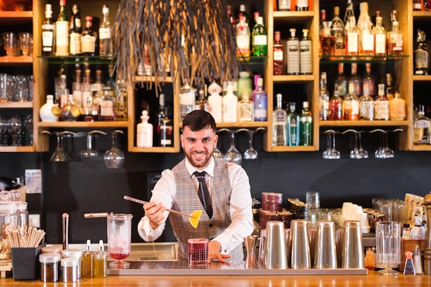 Jeune barman préparant des cocktails très marquants pour ses clients et que le public apprécie Concept Lifestyle boit du temps libre