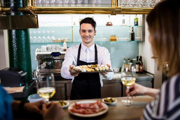 Jeune barman servant de la nourriture aux clients au comptoir