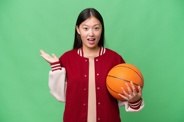 Jeune basketteur femme asiatique sur fond isolé avec une expression faciale choquée