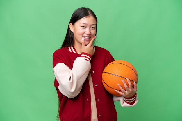 Jeune basketteur femme asiatique sur fond isolé heureux et souriant