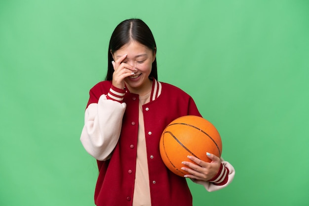 Jeune basketteur femme asiatique sur fond isolé en riant