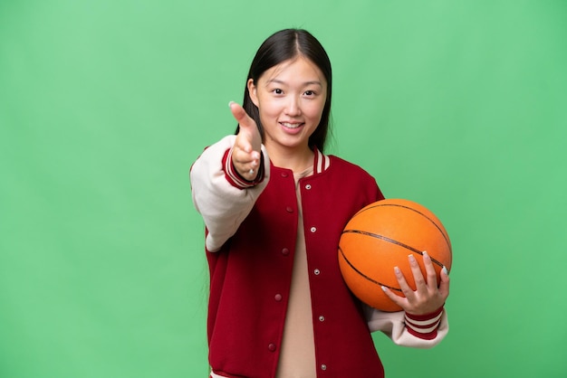 Jeune basketteur femme asiatique sur fond isolé se serrant la main pour conclure une bonne affaire
