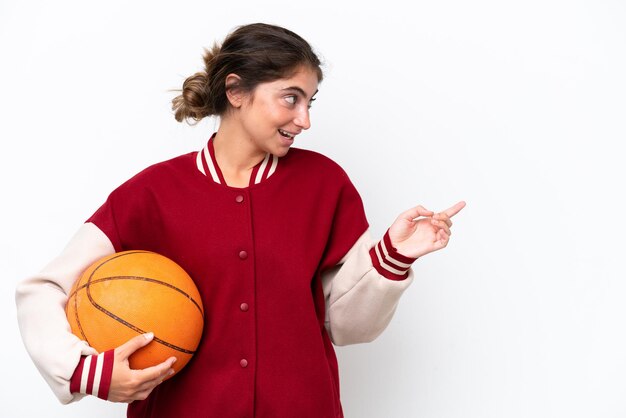 Jeune basketteur femme isolée sur fond blanc pointant le doigt sur le côté et présentant un produit