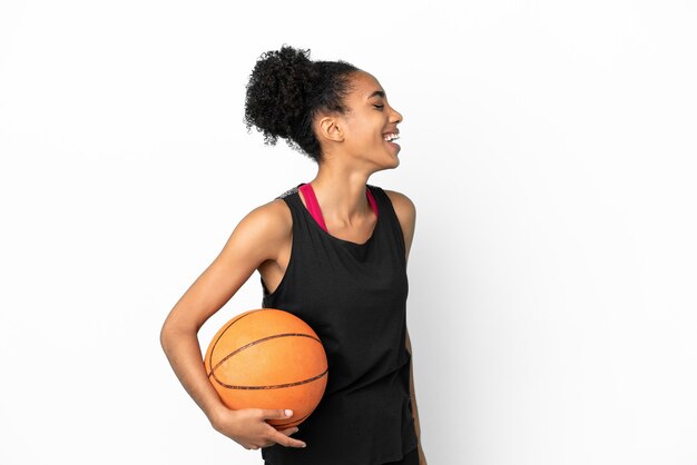 Jeune basketteur femme latine isolée sur fond blanc en riant en position latérale