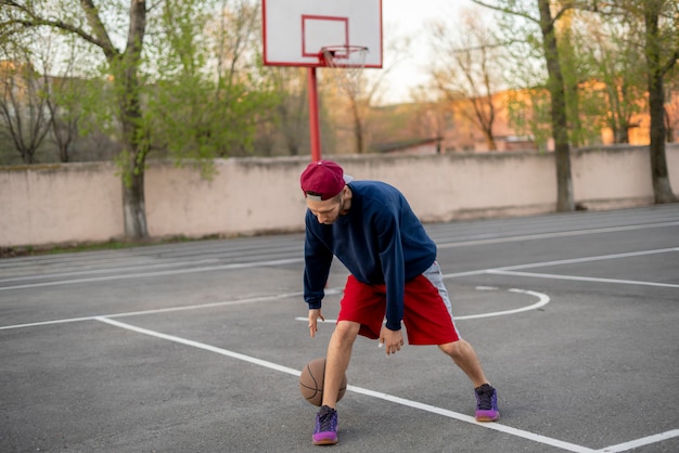 Jeune basketteur s&#39;entraînant à dribbler en plein air sur le court d&#39;asphalte