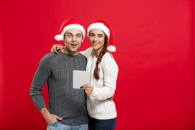 Jeune beau et beau couple aime jouer sur une tablette dans le jour de Noël.