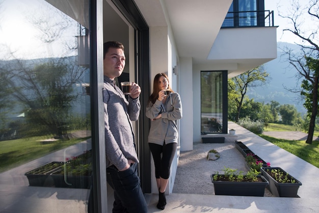 jeune beau beau couple appréciant le café du matin à la porte de leur villa de luxe