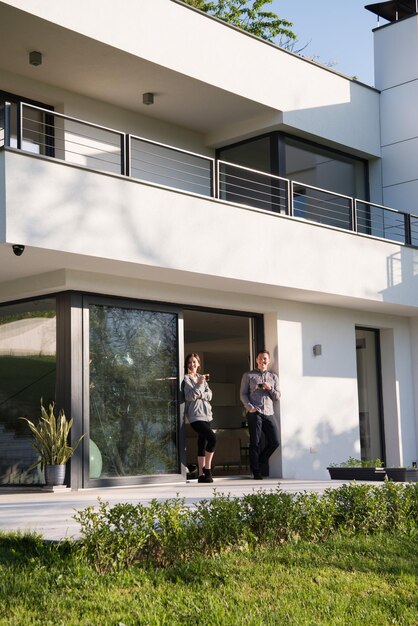 jeune beau beau couple appréciant le café du matin à la porte de leur villa de luxe